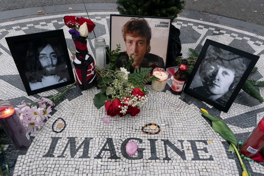 Photos, flowers and candles are left at Strawberry Fields in New York's Central Park to remember John Lennon, Tuesday, Dec. 8, 2020, in New York. The rock star and former Beatle was shot to death outside his New York City apartment building by a fan on Dec. 8, 1980. (AP Photo/Mark Lennihan)