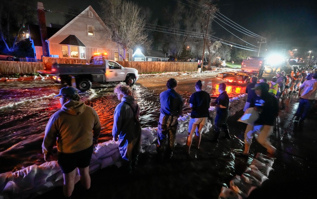 (Francisco Kjolseth | The Salt Lake Tribune) People work to protect homes into the night along 1700 South in Salt Lake City from the rising flow of Emigration Creek through Wasatch Hollow Park on Wednesday, April 12, 2023. 