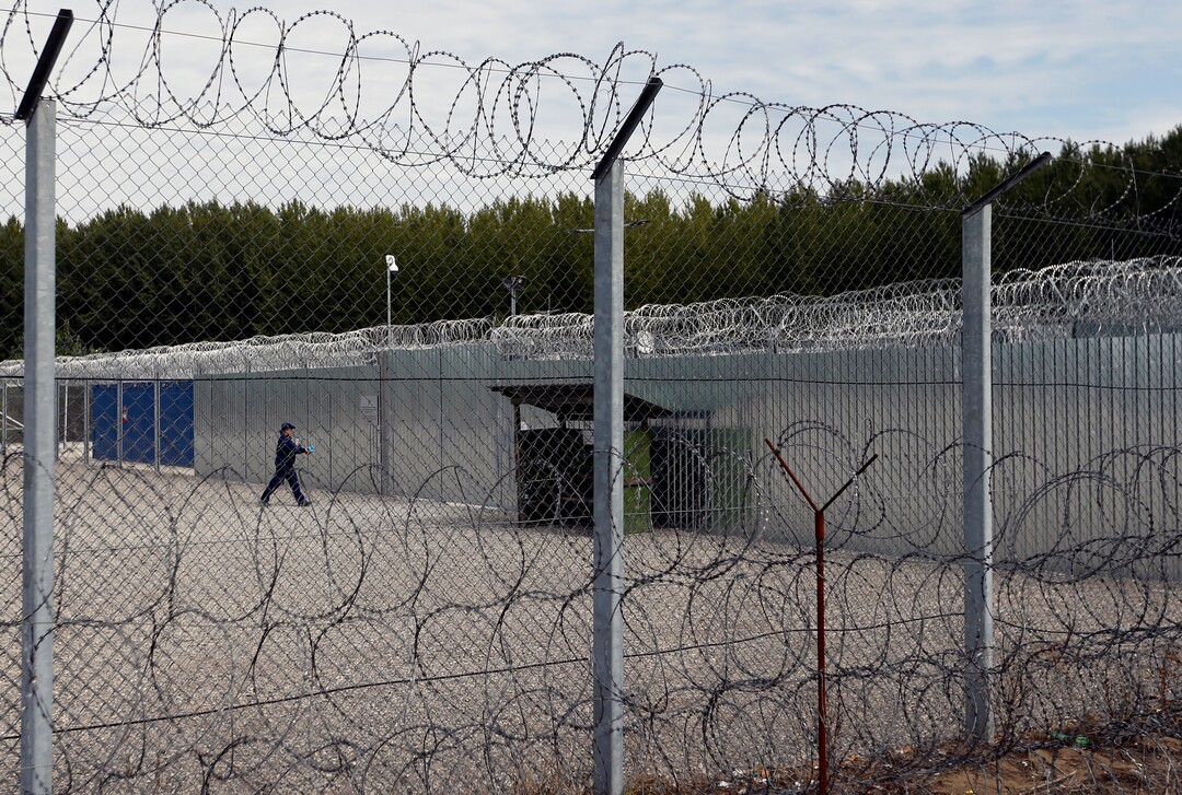 A member of the armed security guard walks trough the yard of the heavily guarded camp at Serbia's border with Hungary, near the Horgos border crossing, Serbia, Tuesday, Sept. 19, 2017. The European Union border that saw hundreds of thousands of migrants enter freely in 2015 has since become a sealed fortress with two rows of fence and closed border camps that the United Nations have described as “in effect detention centers.” (AP Photo/Darko Vojinovic)