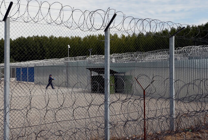 A member of the armed security guard walks trough the yard of the heavily guarded camp at Serbia's border with Hungary, near the Horgos border crossing, Serbia, Tuesday, Sept. 19, 2017. The European Union border that saw hundreds of thousands of migrants enter freely in 2015 has since become a sealed fortress with two rows of fence and closed border camps that the United Nations have described as “in effect detention centers.” (AP Photo/Darko Vojinovic)