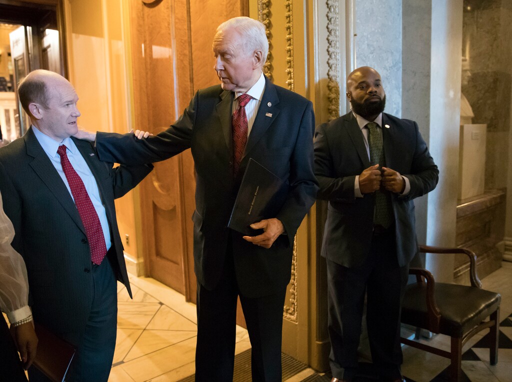 Senate Finance Committee Chairman Orrin Hatch, R-Utah, center, talks with Sen. Chris Coons, D-Del., left, as they leave the chamber following a vote, on Capitol Hill, in Washington, Thursday, Dec. 14, 2017. (AP Photo/J. Scott Applewhite)