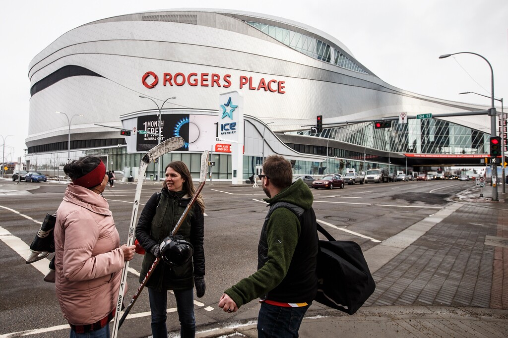 FILE - In this March 12, 2020, file photo, people talk outside Rogers Place, the home ice of the NHL hockey club Edmonton Oilers, in Edmonton, Alberta. (Jason Franson/The Canadian Press via AP, File)