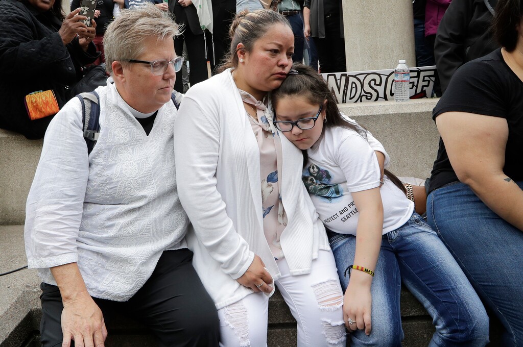 (Elaine Thompson | AP) Gethsemane Lutheran Church Pastor Joanne Engquist, left, sits with Susana Robles and her daughter Natalie Robles, after their husband and father, Jose Robles, turned himself in to immigration authorities in Tukwila, Wash., on Wednesday, July 17, 2019. The prospect of nationwide immigration raids has provided evidence that legions of pastors, rabbis and their congregations stand ready to help vulnerable immigrants with offers of sanctuary and other services.