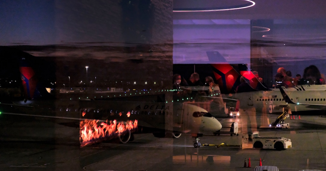 (Leah Hogsten  |  The Salt Lake Tribune) The Salt Lake City International Airport commemorated its 100-year anniversary, Dec. 21, 2020. Reflections of party attendees are reflected in the glass within the Greeting Room as a Delta Jet backs out of the hub.