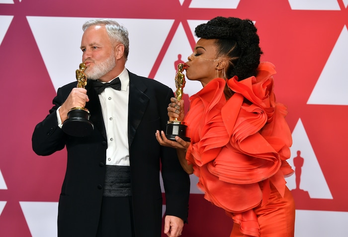 Jay Hart, left, and Hannah Beachler kiss their awards for best production design for "Black Panther" in the press room at the Oscars on Sunday, Feb. 24, 2019, at the Dolby Theatre in Los Angeles. (Photo by Jordan Strauss/Invision/AP)