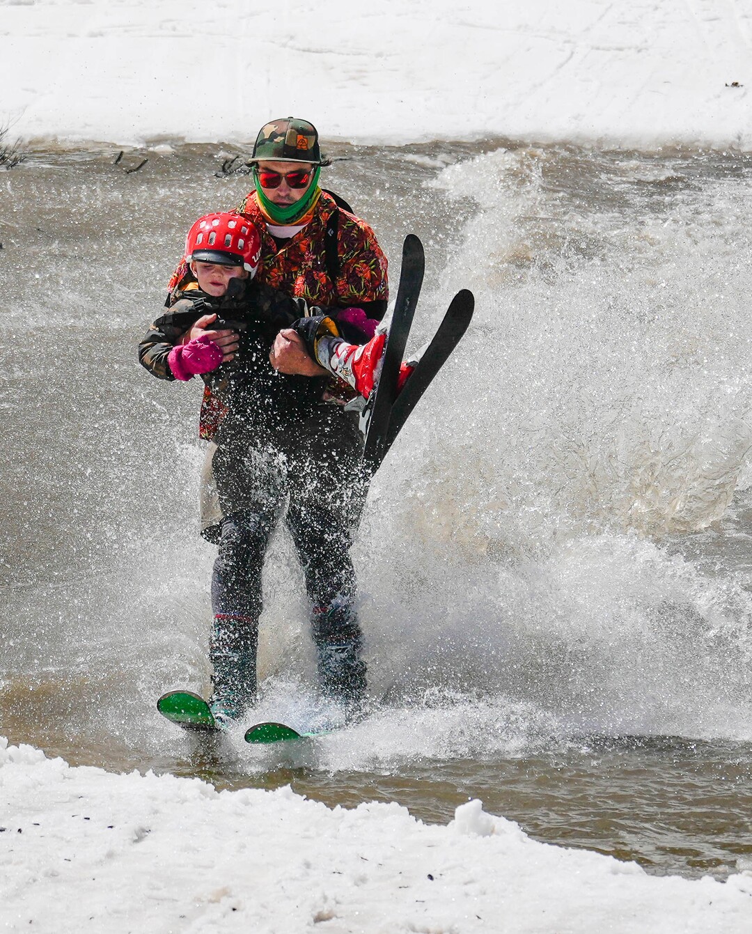 (Francisco Kjolseth  | The Salt Lake Tribune) Sean Mullaney carries his son Lowell, 3, as they skim across the pond in Peruvian Gulch as Snowbird closes the book on the 2024-25 ski season on Monday, May 26, 2025. Snow and sun revelers took to the slushy slopes on Memorial Day as the resort was the last in the state to close.