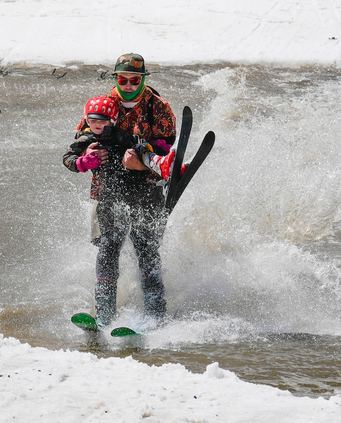 (Francisco Kjolseth  | The Salt Lake Tribune) Sean Mullaney carries his son Lowell, 3, as they skim across the pond in Peruvian Gulch as Snowbird closes the book on the 2024-25 ski season on Monday, May 26, 2025. Snow and sun revelers took to the slushy slopes on Memorial Day as the resort was the last in the state to close.