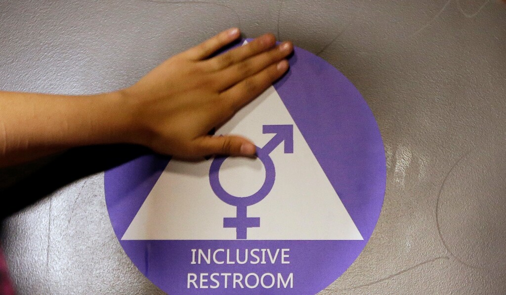 FILE - In this May 17, 2016 file photo, a new sticker is placed on the door at the ceremonial opening of a gender neutral bathroom at Nathan Hale High School in Seattle. Hundreds of parents across the country have called on President Donald Trump to embrace Obama-era protections for transgender students that call for letting them use school bathrooms in accordance with their gender identity. In a letter, sent to the president by the Human Rights Campaign late Tuesday, Feb. 14, 2017, more than 780 parents stressed that "all students deserve equal access to a safe, welcoming school and a high quality education no matter who they are." (AP Photo/Elaine Thompson, File)