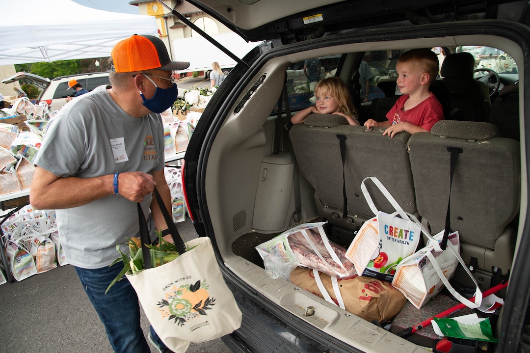 (Francisco Kjolseth  |  The Salt Lake Tribune) Potato farmer Bryan Searle is greeted by young kids as he loads a family’s car with food for the third “Miracle Project” for the nonprofit foundation which raises money to purchase food produced by Utah farmers and then gives to residents in need, takes place at the Utah State Fairpark in Salt Lake City on Monday, July 27, 2020. The food donation from the Utah Farm Bureau’s “Farmers Feeding Utah” program provided food for 600 individuals and families who have recently become unemployed due to the coronavirus.