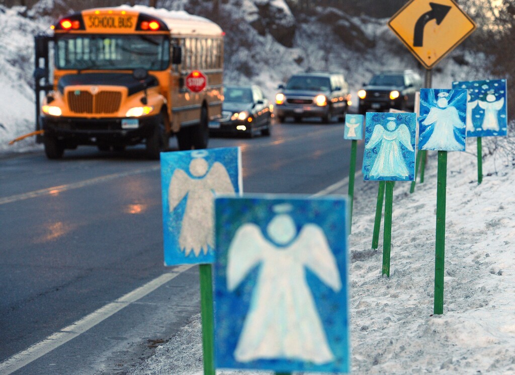 FILE - In this Jan. 3, 2013, file photo, a bus traveling from Newtown, Conn., to Monroe stops near 26 angel signs posted along the roadside in Monroe, Conn., on the first day of classes for Sandy Hook Elementary School students since the Dec. 14, 2012, shooting. The massacre in Newtown, in which a mentally troubled young man killed 26 children and teachers, served as a rallying cry for gun-control advocates across the nation. But in the three years since, many states have moved in the opposite direction, embracing the National Rifle Associations axiom that more good guys with guns are needed to deter mass shootings. (AP Photo/Jessica Hill, File)