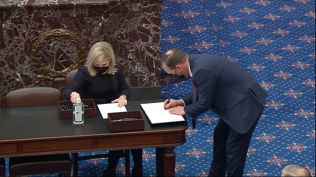 (Senate Television via AP) In this image from video, Sen. Mike Lee, R-Utah, signs the oath book after being sworn in for the impeachment trial of former President Donald Trump in the Senate at the U.S. Capitol in Washington, Tuesday, Jan. 26, 2021.