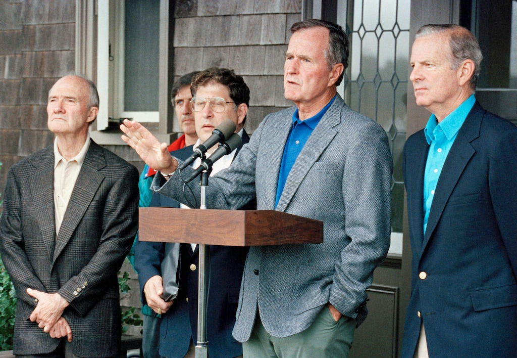 (Doug Mills | AP photo)
In this August 11, 1990, photo, President George H. W. Bush comments to reporters at his Kennebunkport home in Maine, after meeting with his advisers on the Middle East crisis. Listening from left, are National Security Adviser Brent Scowcroft, White House Andy Card (partially hidden), Chief of Staff John Sununu, and Secretary of State James Baker III.