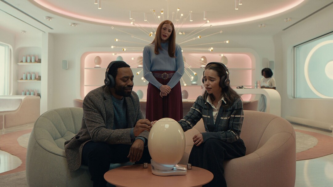 (Andrij Parekh  |  Sundance Institute) A couple (Chiwetel Ejiofor, left, and Emilia Clarke, right) learn from a saleswoman (Rosalie Craig, center), about a new form of parenthood — a detachable artificial womb — in director Sophie Barthes' "The Pod Generation," an official selection of the Premieres program at the 2023 Sundance Film Festival.
