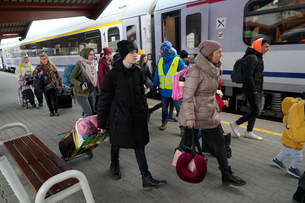 (Sergei Grits | AP) Refugees with children walk along a platform after fleeing the war from neighboring Ukraine at a railway station in Przemysl, Poland, on Friday, March 25, 2022.