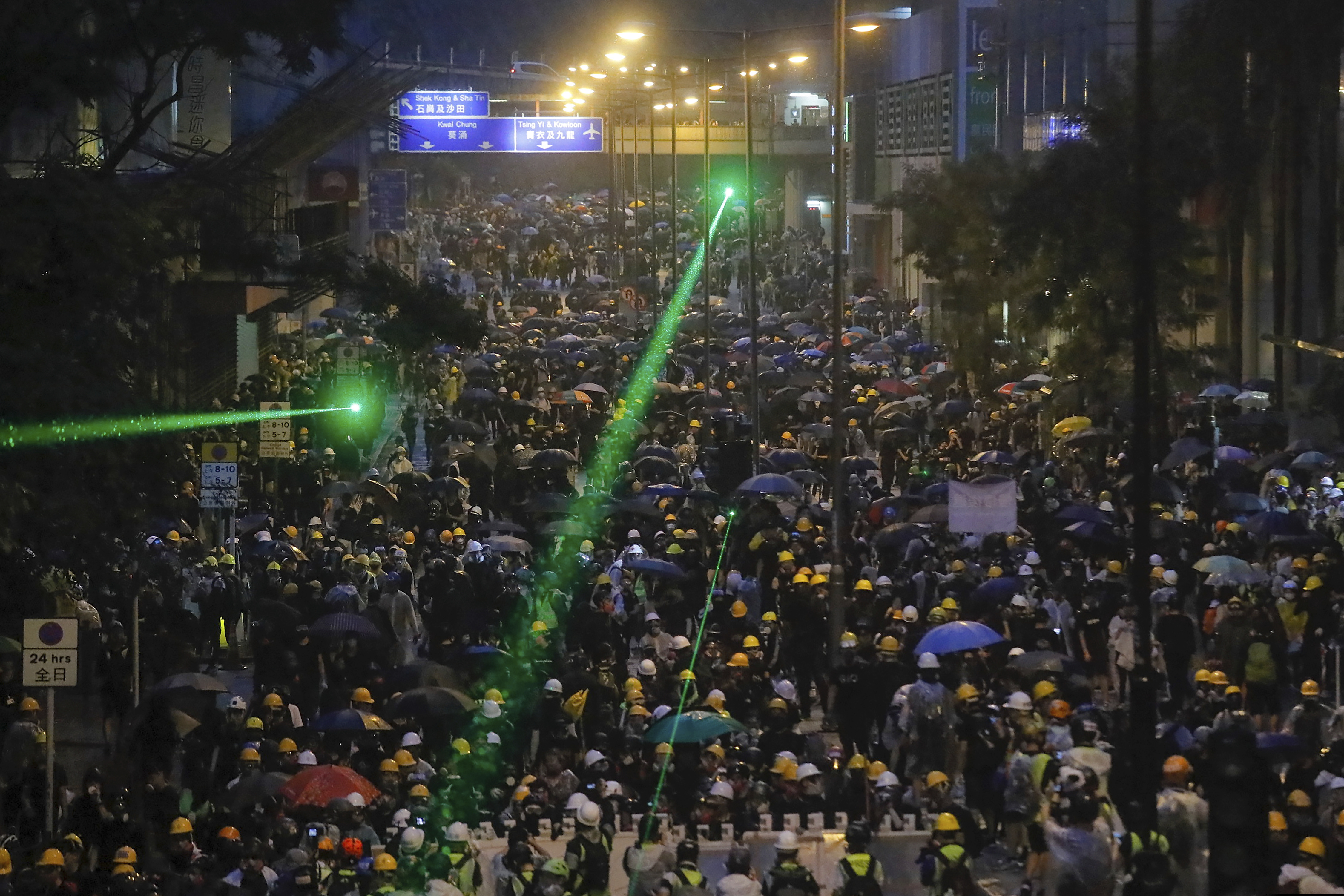 (Kin Cheung | AP) Demonstrators, some using laser pointers toward police lines, gather during a protest in Hong Kong, Sunday, Aug. 25, 2019. Hong Kong police rolled out water cannon trucks for the first time in this summer's pro-democracy protests. The two trucks moved forward with riot officers Sunday evening as they pushed protesters back along a street in the outlying Tsuen Wan district.