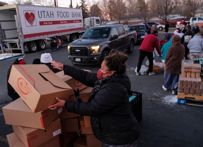 (Leah Hogsten | The Salt Lake Tribune) Volunteer Viata Vatuvei, center, helps hand out food from the Utah Food Bank to needy families, Dec. 23, 2020.