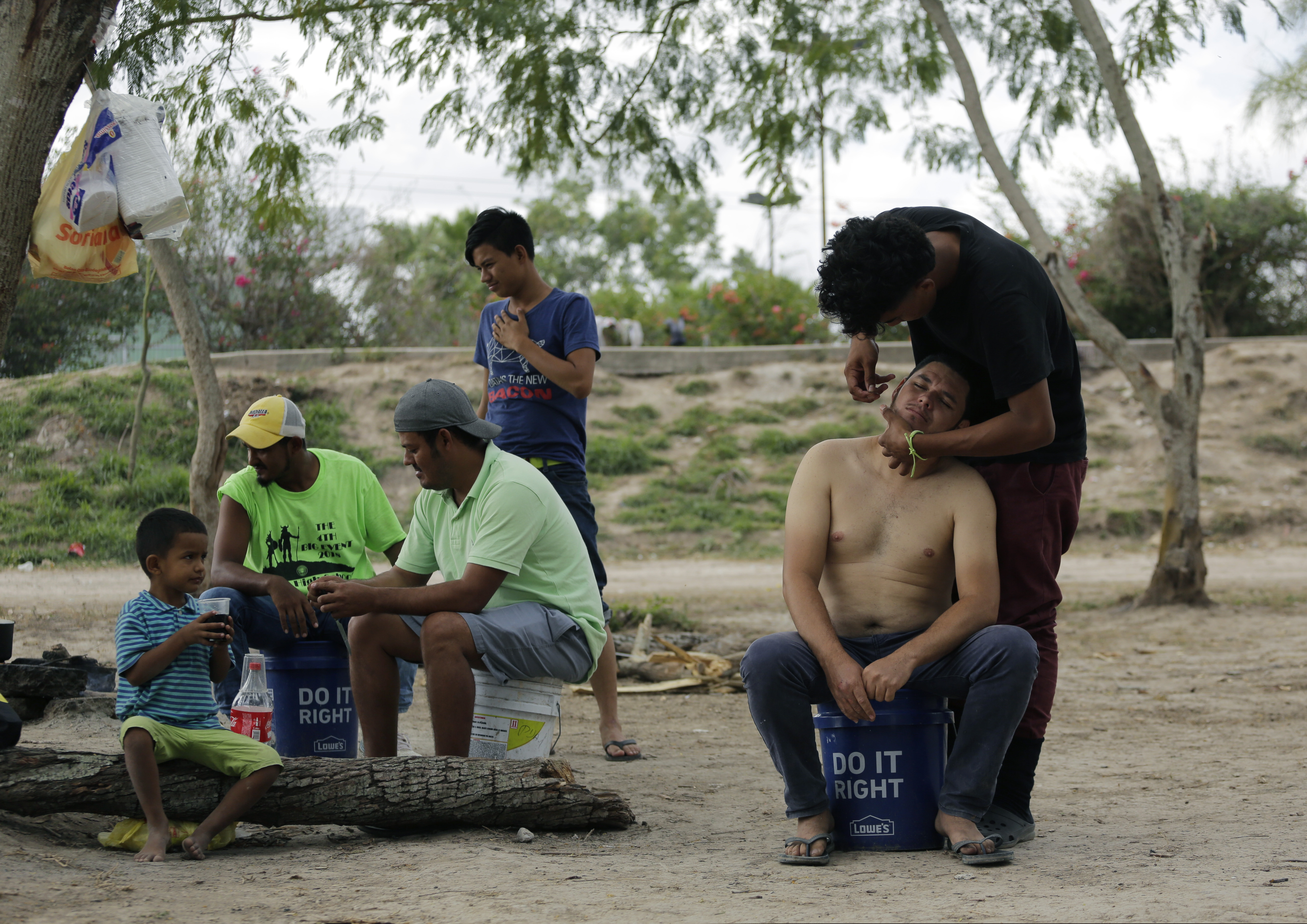 In this Wednesday, Nov. 6, 2019, migrants create a makeshift barbershop as they live in a refugee camp in Matamoros, Mexico. The camp is an outgrowth of the Trump administration’s “Remain in Mexico” policy, in which more than 55,000 migrants have been told to wait and pursue their cases south of the border. (AP Photo/Eric Gay)