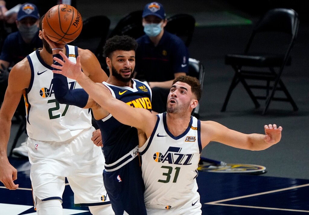 Utah Jazz forward Georges Niang, right, fouls Denver Nuggets guard Jamal Murray, center, while pursuing the ball in the first half of an NBA basketball game Sunday, Jan. 17, 2021, in Denver. (AP Photo/David Zalubowski)