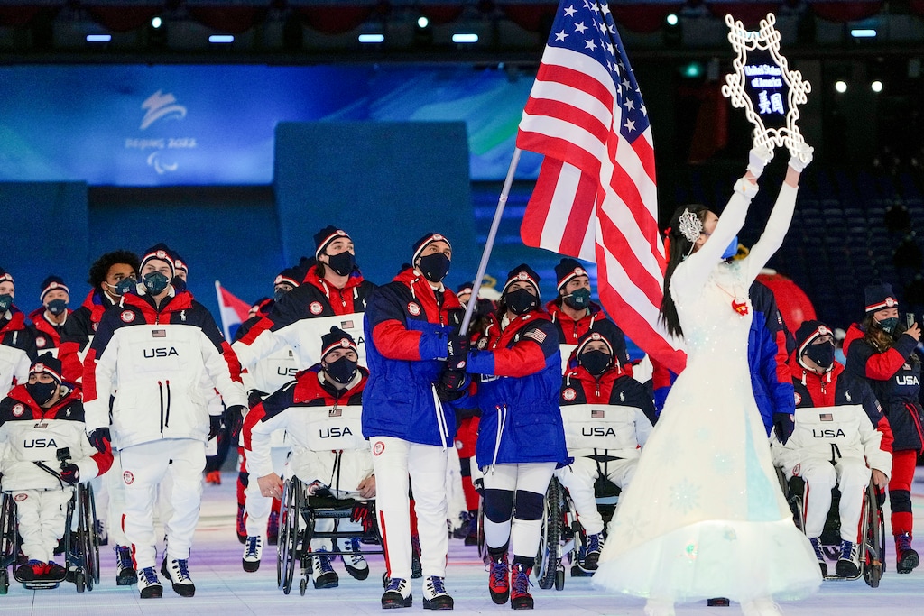 (Andy Wong | AP) Danelle Umstead and Tyler Carter of the United States carry the flag as they arrive for the opening ceremony at the 2022 Winter Paralympics, Friday, March 4, 2022, in Beijing.