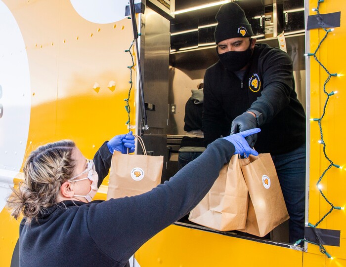 (Rick Egan | The Salt Lake Tribune)  Sid Burgos hands a bag of grilled cheese sandwiches to Sharlene Heward, to be delivered to 600 health care workers as part of the the Curds + Kindness program, which supports local dairy farmers, at the South Jordan Health Center in Daybreak on Tuesday, Dec. 1, 2020.