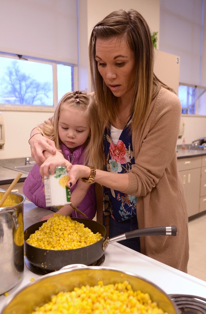 (Leah Hogsten  |  The Salt Lake Tribune) Granite Park Junior High assistant principal Megan Madsen empties cans of corn with her daughter Harper, 3.  Sixteen members of Granite Park Junior High SchoolÕs faculty prepared and served a hot spaghetti meal to students and their families, Friday, December 22, 2017 at the school for the inaugural ÔDinner at the Park.' Roughly 90 percent of students who attend Granite Park Junior High in South Salt Lake qualify for free or reduced lunch through the federal school lunch program. Knowing the challenges faced by their students, staff members at Granite Park came up with an idea to help families through the holidays.