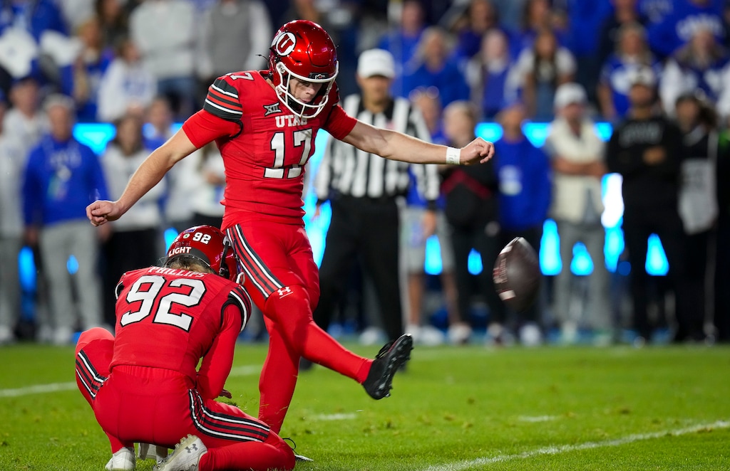(Bethany Baker  |  The Salt Lake Tribune) Utah Utes kicker Dillon Curtis (17) kicks the ball as Utah Utes punter Orion Phillips (92) assists during the game between the BYU Cougars and the Utah Utes in Provo on Saturday, Oct. 18, 2025.
