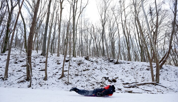 A man sleds down a road at Radnor Lake State Park, Tuesday, Jan. 16, 2018, in Nashville, Tenn. A winter storm brought snow and cold temperatures to the area, causing the closing of schools and businesses. (AP Photo/Mark Humphrey)