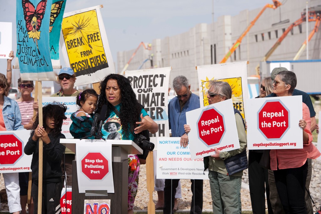 (Ed Kosmicki | Special to The Tribune) Avā 'Aikona decries the state's plan of an inland port at a news conference in front of a huge, recently completed Amazon fufillment center Thursday, June 10, 2021. With Afa are her son, Tangata 'Olakepa Tavai, 7, and her daughter Pele Tavai, 4. About three dozen people attended the conference listening to five speakers depsite gusting winds that elimated a banner the group hoped to display.