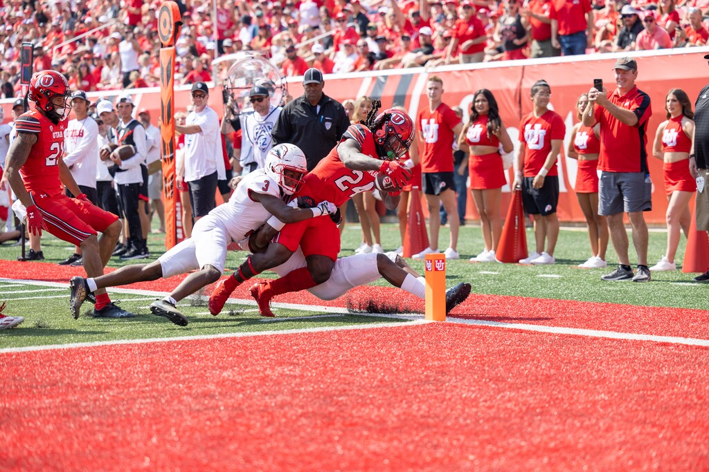 (University of Utah Athletics) Utah running back Chris Curry scores a touchdown while being tackled by two Souther Utah defenders during the game on Saturday, Sept. 10, 2022, at Rice-Eccles Stadium.