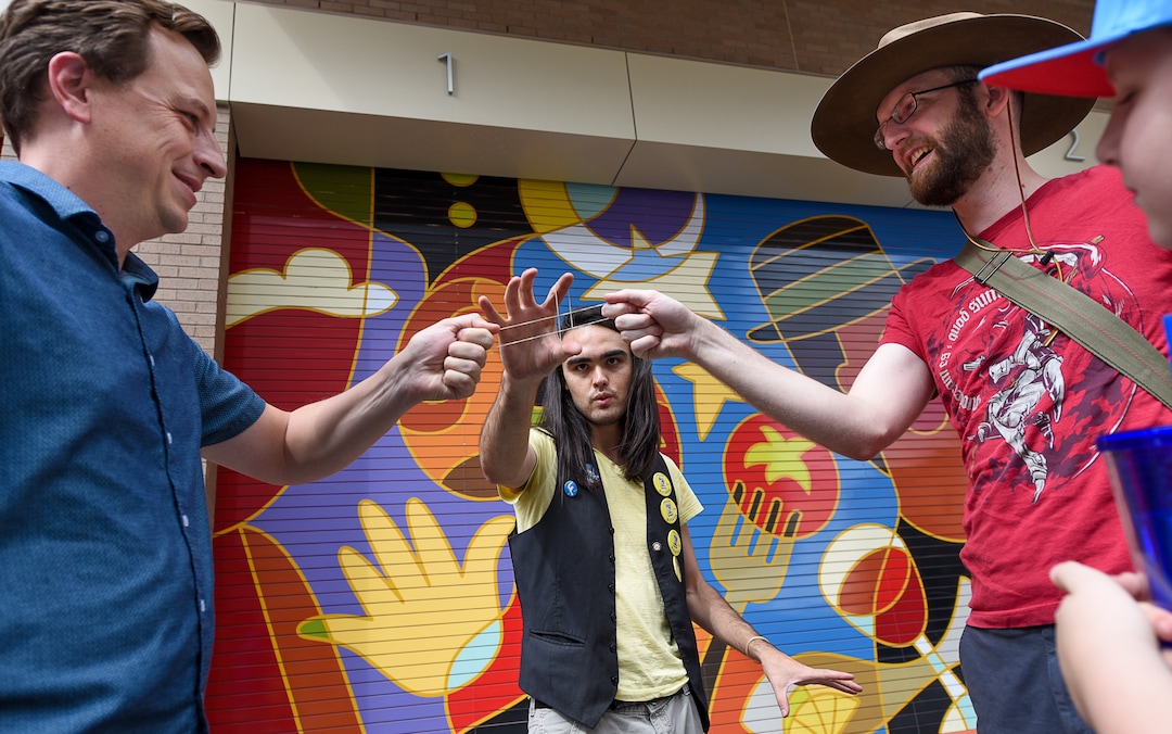 (Francisco Kjolseth  |  The Salt Lake Tribune)  Magician David DeCarolis, center, performs a magic trick with Jeff Greenland, left, and Ransom Smith as the Salt Lake Arts Council presents the first Busker Fest, featuring entertainers, dancers, musicians, magicians, jugglers, and comedy to celebrate the tradition of street performance and observe the city's vaudeville roots along Regent Street in downtown Salt Lake City on Friday, Aug. 24, 2018.