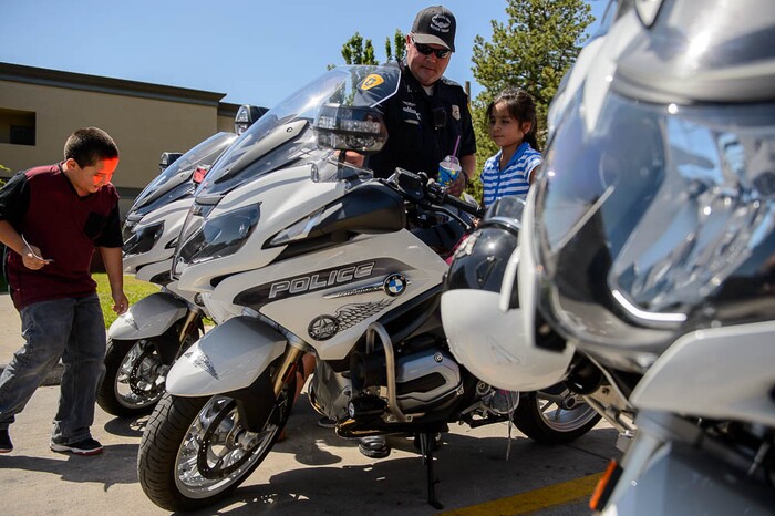 (Trent Nelson | The Salt Lake Tribune)Mia Cardenes takes a turn on Salt Lake City police officer Michael Blackburn's bike Wednesday June 13, 2018, during an event at a Salt Lake City 7-Eleven store promoting the donation of 7,500 Slurpee coupons by the company for police officers to hand out to children. At left is Mario Cardenes.