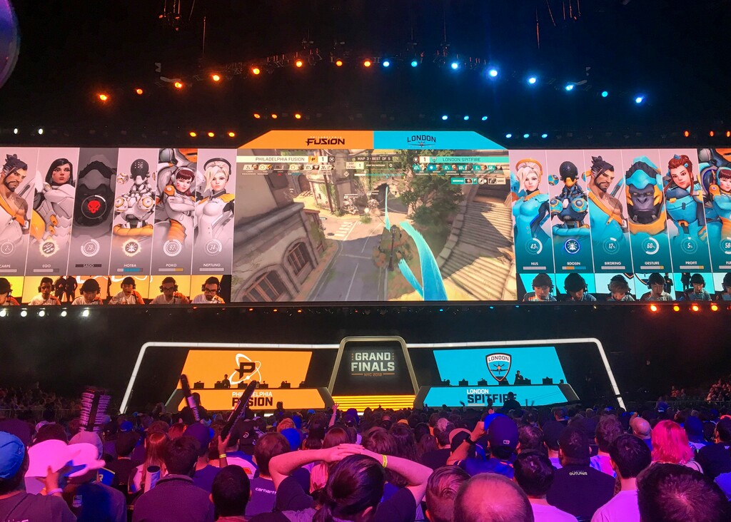 In this Friday, July 27, 2018 photo, fans watch the Philadelphia Fusion and London Spitfire compete in the Overwatch League Grand Finals' first night of competition at the Barclays Center in the Brooklyn borough of New York. The Overwatch League is making a grand gamble: that its deep pockets and massive infrastructure can keep it atop the esports mountain even as Fortnite comes charging for the crown. (AP Photo/Terrin Waack)