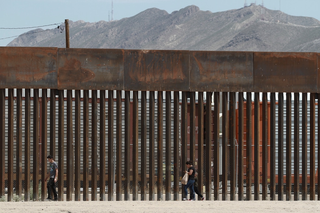 (Christian Chavez | AP file photo) In this July 17, 2019 file photo, three migrants who had managed to evade the Mexican National Guard and cross the Rio Grande onto U.S. territory walk along a border wall set back from the geographical border, in El Paso, Texas, as seen from Ciudad Juarez, Mexico.