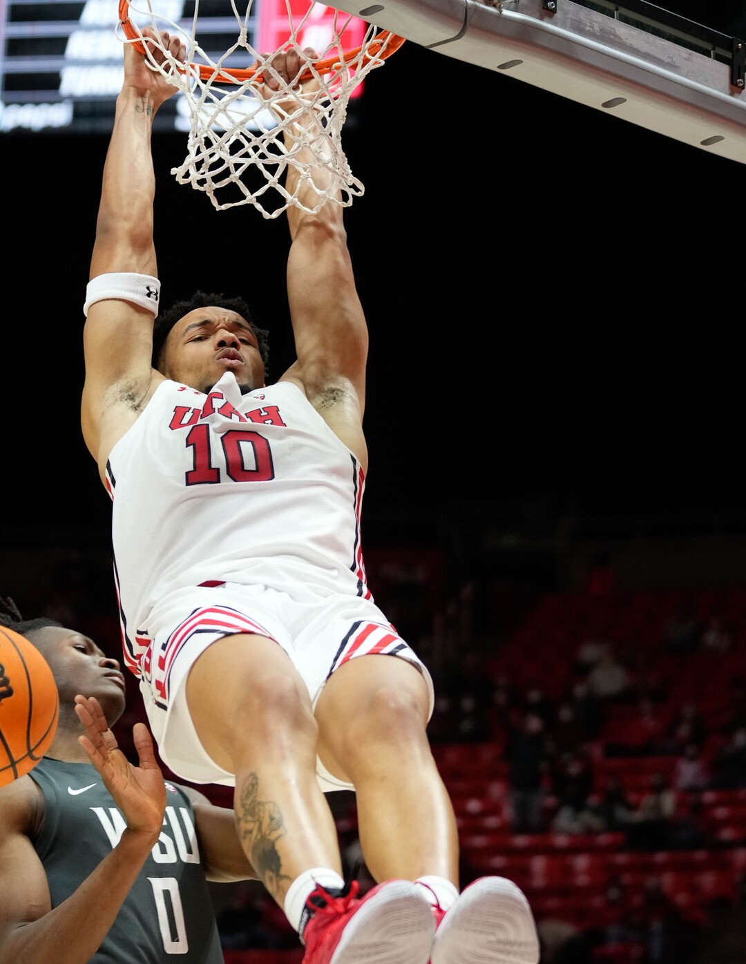 (Francisco Kjolseth | The Salt Lake Tribune) Utah Utes guard Marco Anthony (10) holds on to the rim following a dunk over the Washington State Cougars in an NCAA college basketball game at the Jon M.Huntsman Center, on Saturday, Jan. 8, 2022. Utah lost 61-77.