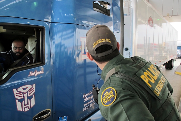 Border Patrol agent Eric Mendoza speaks to the driver of a tractor-trailer waiting to pass through the Laredo North vehicle checkpoint in Laredo, Texas, on Friday, Feb. 2, 2018. Agents say the checkpoint is sometimes overwhelmed by traffic, making it a certainty that some smugglers get through. (AP Photo/Nomaan Merchant)