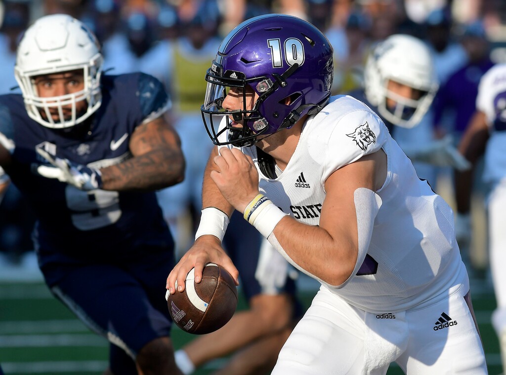 (Eli Lucero/The Herald Journal via AP) Weber State quarterback Bronson Barron (10) scrambles out of the pocket as Utah State defensive end Daniel Grzesiak (9) defends in the first half of an NCAA college football game Saturday, Sept. 10, 2022, in Logan, Utah.
