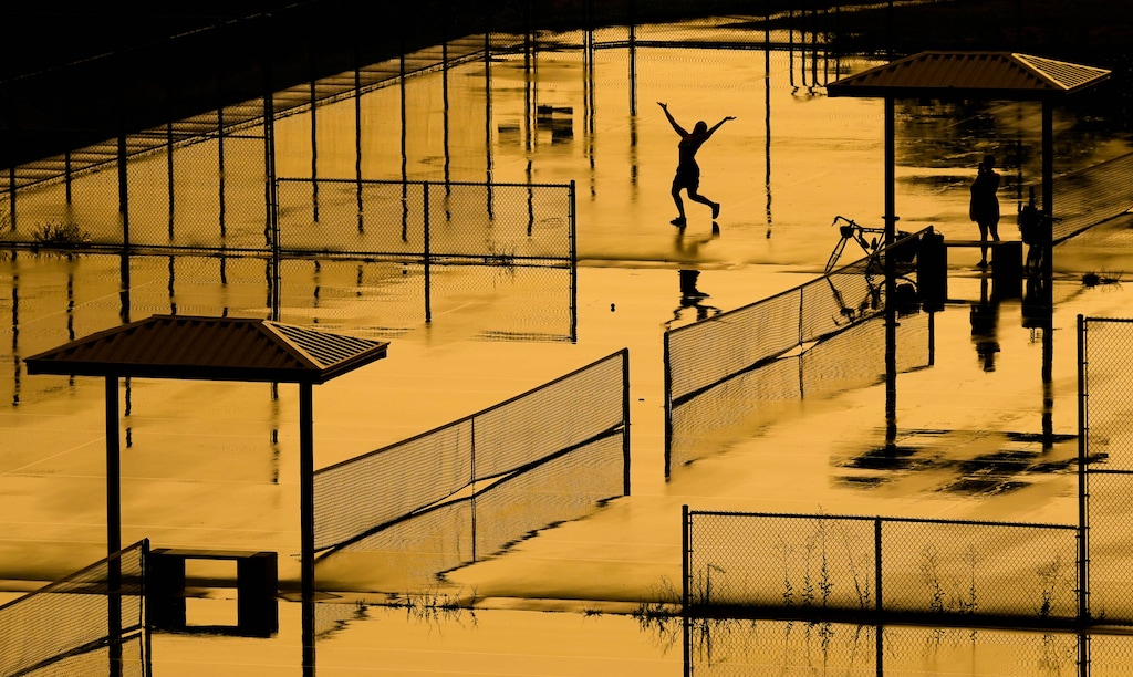 (Francisco Kjolseth | The Salt Lake Tribune) People dance in the rain on the courts of Eleventh Avenue Park in Salt Lake City as the setting sun lights up the sky in a warm glow, Wednesday, July 29, 2026. Utahns are bracing for another weekend of triple-digit temperatures.