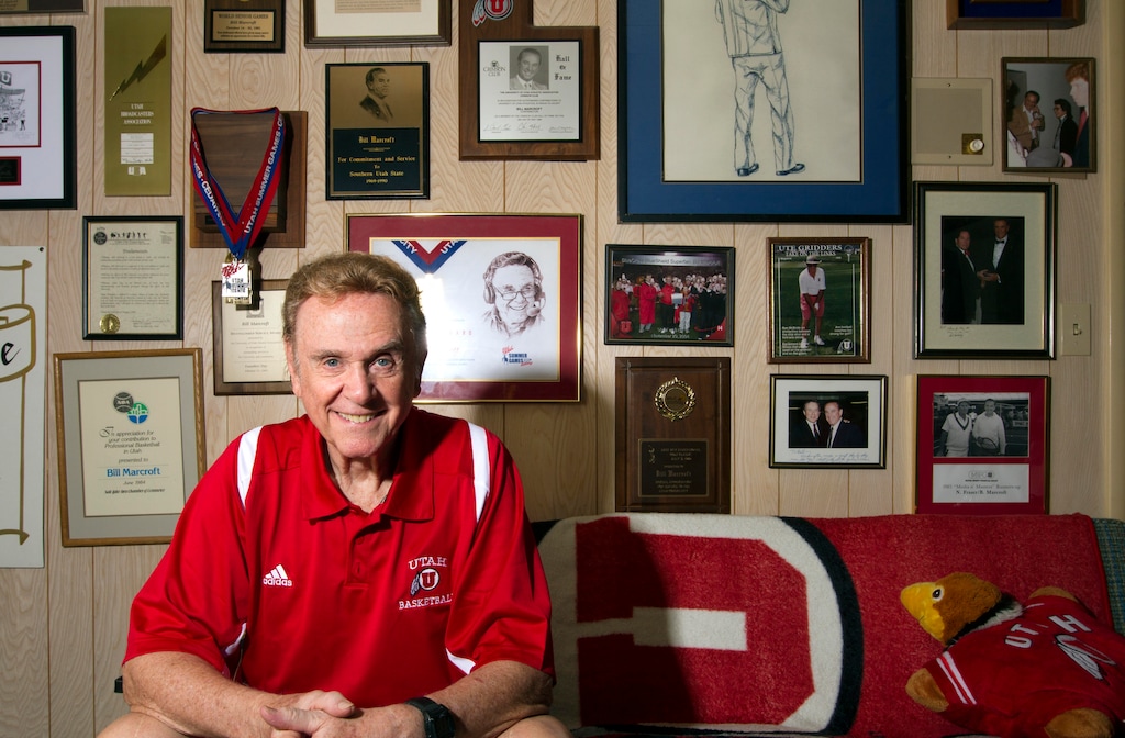 (Photo courtesy of the University of Utah) Bill Marcroft, the play-by-play broadcaster for Utah football and men’s basketball for 38 years, sits in the office of his home in Millcreek, Utah, July 26, 2014, among the memorabilia and accolades he received over the course of his storied career.