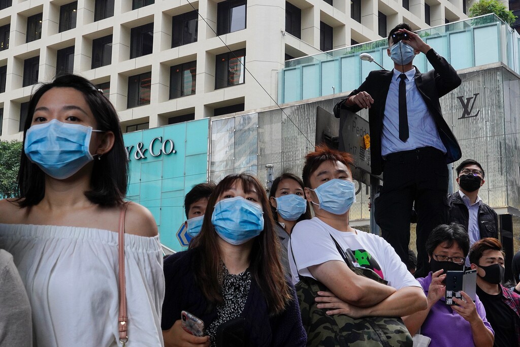 (Vincent Yu | AP) In this Nov. 12, 2019 file photo, people wearing face masks watch pro-democracy protesters in Central, Hong Kong. In 2019, face masks were the signature of Hong Kong’s protesters, who wore them to protect against tear gas and conceal their identities from authorities. These same masks are now ubiquitous around the world -- a hallmark of the spreading coronavirus worn by people from China and Iran, to Italy and America, seeking to protect against the new coronavirus. The vast majority of people recover from the new virus.