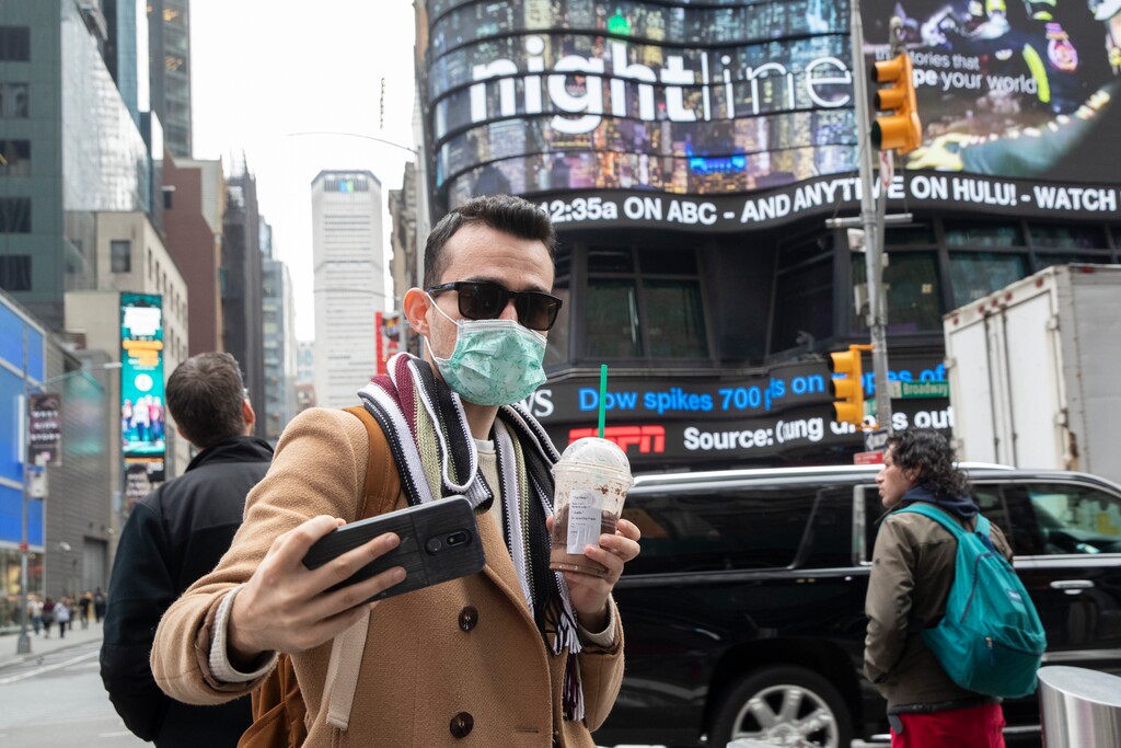 Justin Dalipi, of Albania, wears a mask as a precaution against the Corona virus during the final days of his visit to New York, as he takes a selfie in New York's Times Square, Tuesday, March 10, 2020. For most people, the new coronavirus causes only mild or moderate symptoms, such as fever and cough. For some, especially older adults and people with existing health problems, it can cause more severe illness, including pneumonia. The vast majority of people recover from the new virus. (AP Photo/Mary Altaffer)