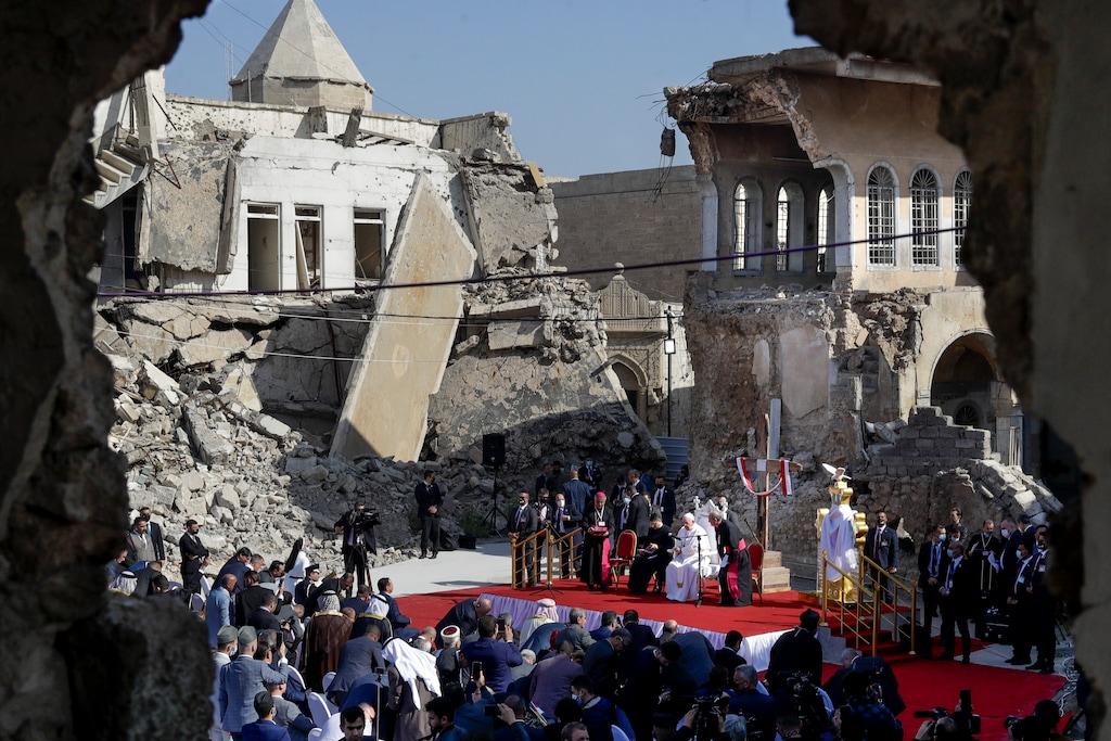 (Andrew Medichini | The Associated Press) Pope Francis, surrounded by shells of destroyed churches, leads a prayer for the victims of war at Hosh al-Bieaa Church Square, in Mosul, Iraq, once the de-facto capital of IS, Sunday, March 7, 2021. The long 2014-2017 war to drive IS out left ransacked homes and charred or pulverized buildings around the north of Iraq, all sites Francis visited on Sunday.
