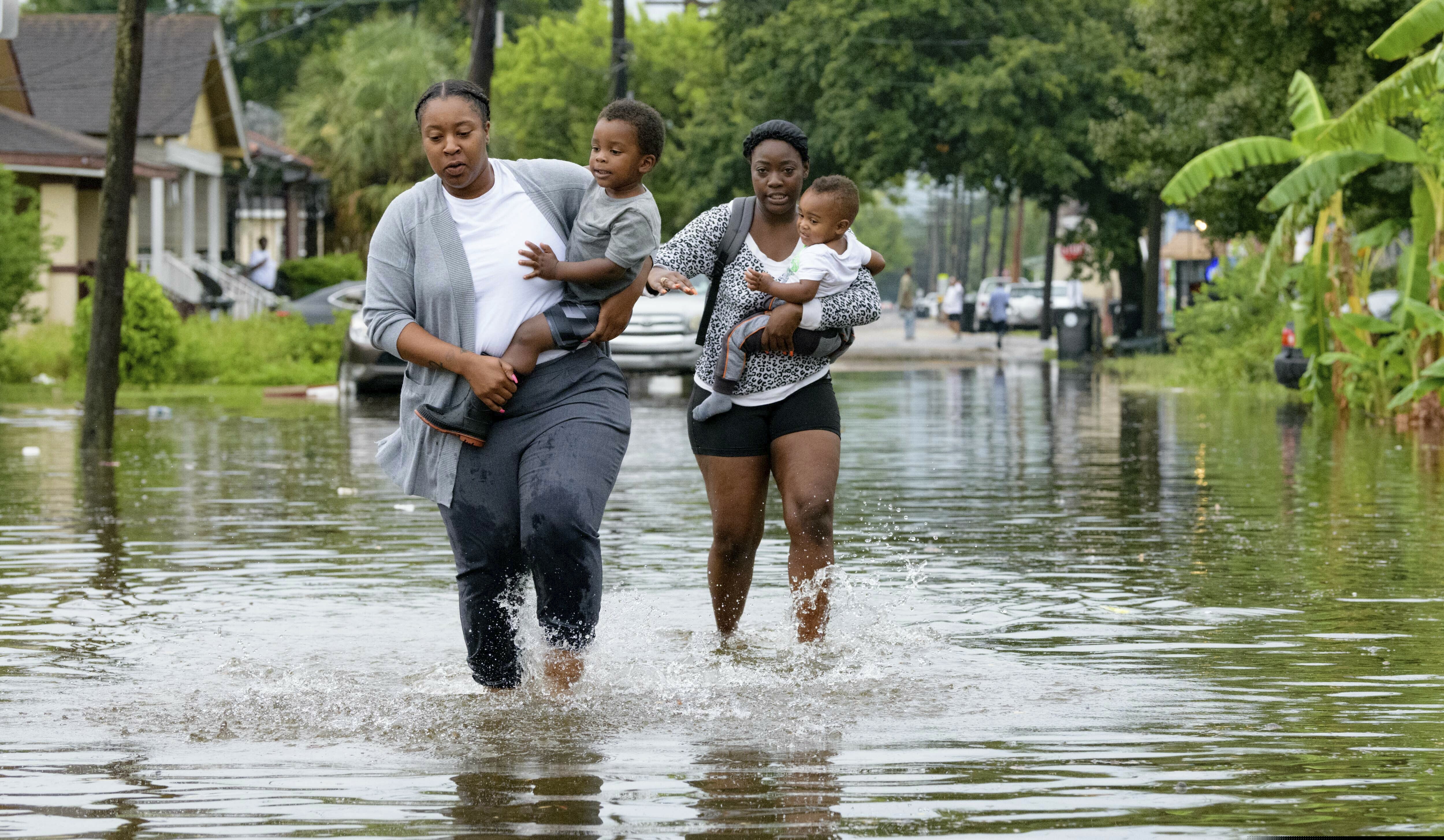 (Matthew Hinton | AP Photo) Jalana Furlough carries her son Drew Furlough as Terrian Jones carries Chance Furlough on Belfast Street near Eagle Street in New Orleans after flooding from a tropical wave system in the Gulf Mexico that dumped lots of rain in Wednesday, July 10, 2019.
