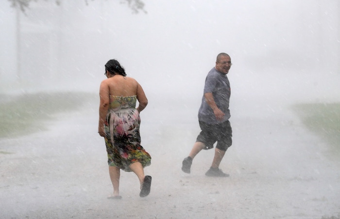 (AP Photo | David J. Phillip) Antonio Barron, right, looks back to his girlfriend, Melissa Rocha, as they run through the street during a band of heavy rain from Hurricane Harvey Saturday, Aug. 26, 2017, in Palacios, Texas.