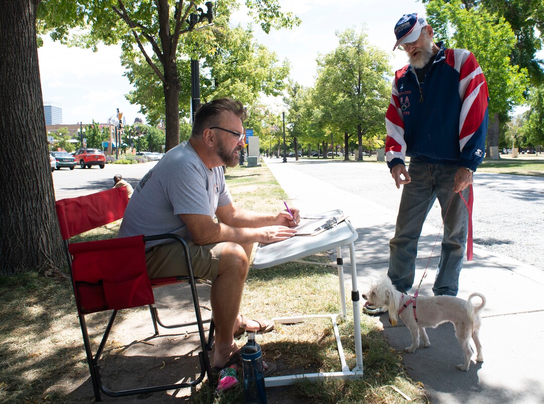 (Rick Egan  |  The Salt Lake Tribune)  Stan Stensrud (left) checks in Giobanni Anotnio and his dog Carmela. Stan is a volunteer for the Street Dawg Crew, a group that gives out food, treats, leashes and things for pets of homeless people every week at Liberty Park, Sunday, July 7, 2019.
