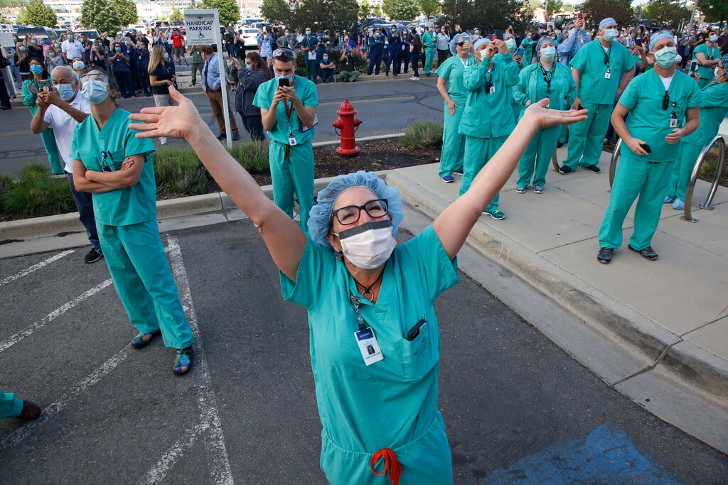 FILE - Healthcare worker Diane Alonso celebrates as a giant American flag is unfurled at Intermountain Medical Center on May 21, 2020, in Murray, Utah, as a way to honor frontline healthcare workers and recognize first responders as they care for COVID-19 patients. Sanford Health and Intermountain Healthcare said Monday, Oct. 26, 2020, they plan to merge companies. If the deal is approved, it would unite Salt Lake City-based Intermountain with operations in Utah, Nevada and Idaho, with Sioux Falls-based Sanford, which operates in 24 states. (AP Photo/Rick Bowmer, File)