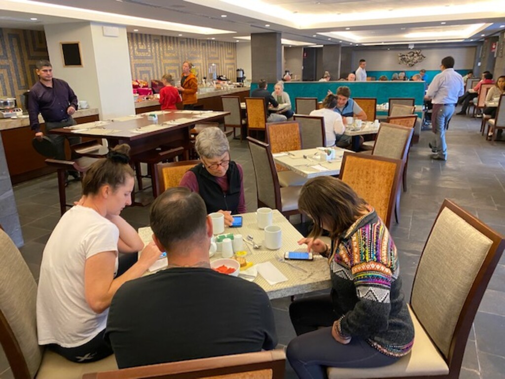 (Courtesy of Stewart Aitchison) Utah resident Ann Aitchison (far side of table) and other stranded travelers search their phones for updates about the closure of Peru's borders, which left them stranded in the  country since Monday.