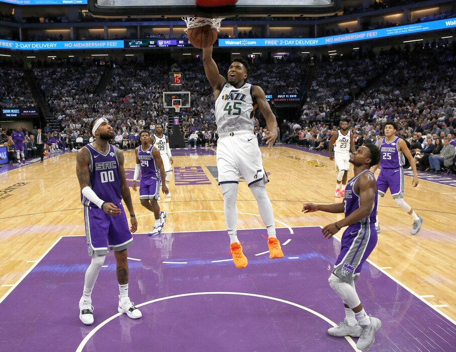 Utah Jazz guard Donovan Mitchell, center, stuffs as Sacramento Kings' Willie Cauley-Stein, left, and Yogi Ferrell, right, look on during the second half of an NBA basketball game Wednesday, Oct. 17, 2018, in Sacramento, Calif. The Jazz won 123-117. (AP Photo/Rich Pedroncelli)