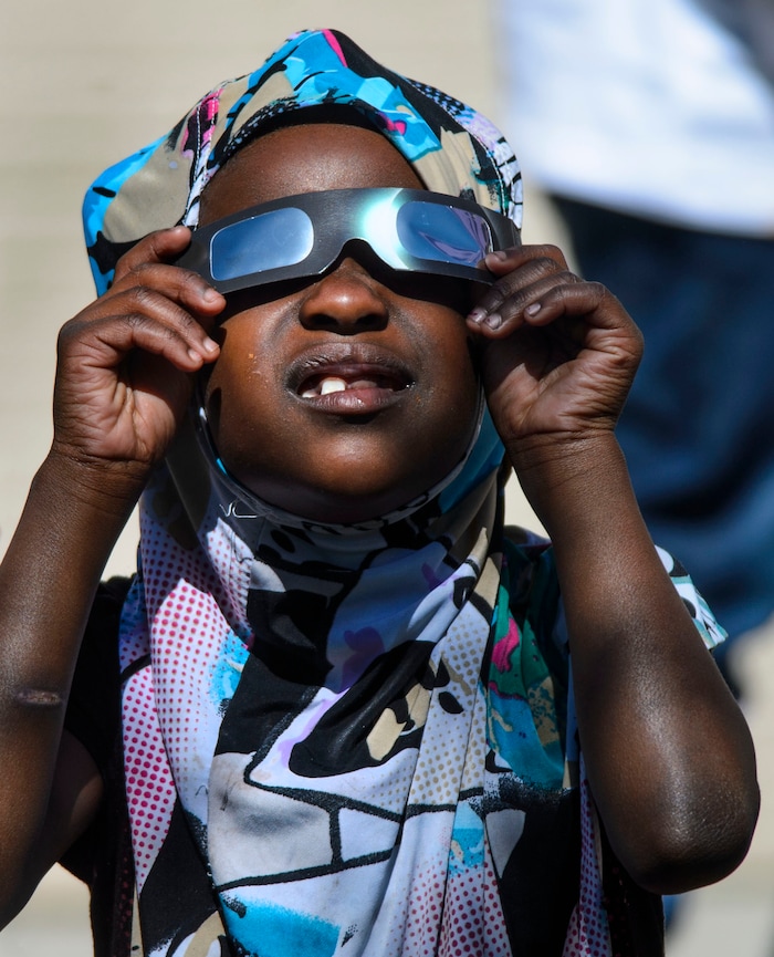 (Steve Griffin  |  The Salt Lake Tribune) Meadowlark Elementary School first-grader Rukia Aden smiles as she watches The Great Eclipse during the Salt Lake School District's first day of the 2017-2018 school year. STEAM teacher-coordinator Wendi Laurence who formerly worked at NASA has been planning an event around the eclipse. All students had glasses to view the event and many had lunch outside at the Salt Lake City school Monday August 21, 2017.