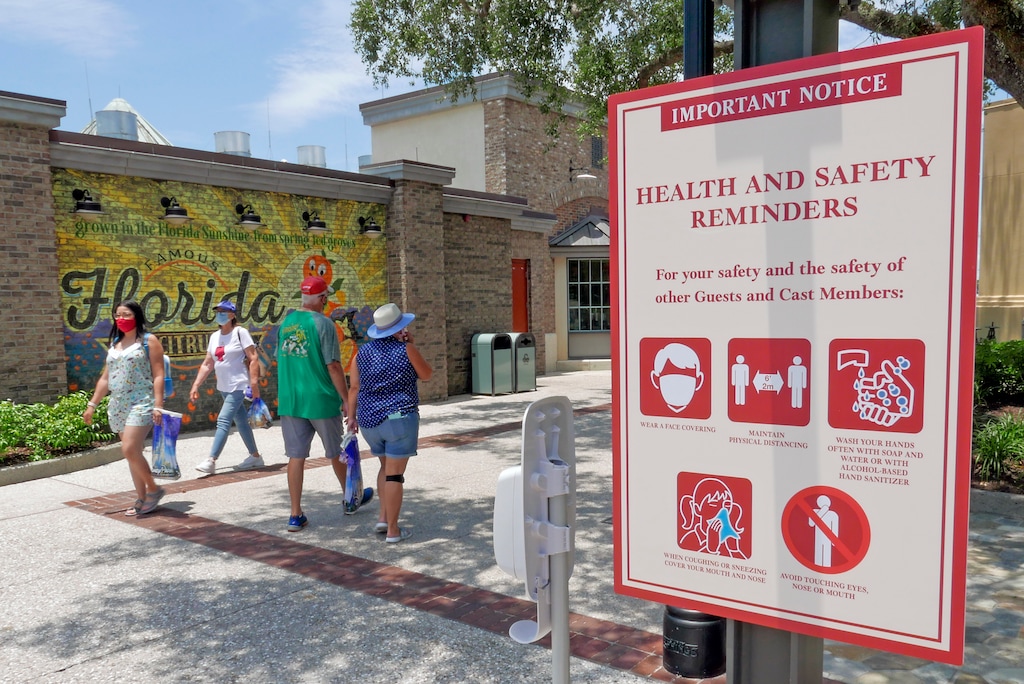 (John Raoux | AP) Signs remind patrons to wear masks and other protocols because of the coronavirus pandemic as they stroll through the Disney Springs shopping, dining and entertainment complex in Lake Buena Vista, Fla., on June 16, 2020. The number of deaths per day from the coronavirus in the U.S. has fallen in recent weeks to the lowest level since late March, even as states increasingly reopen for business. But scientists are deeply afraid the trend may be about to reverse itself.