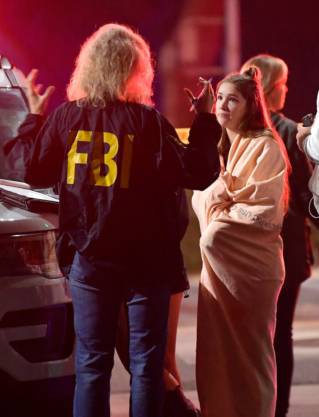An FBI agent talks to a potential witness as they stand near the scene Thursday, Nov. 8, 2018, in Thousand Oaks, Calif. where a gunman opened fire Wednesday inside a country dance bar crowded with hundreds of people on "college night," wounding 11 people including a deputy who rushed to the scene. Ventura County sheriff's spokesman says gunman is dead inside the bar. (AP Photo/Mark J. Terrill)